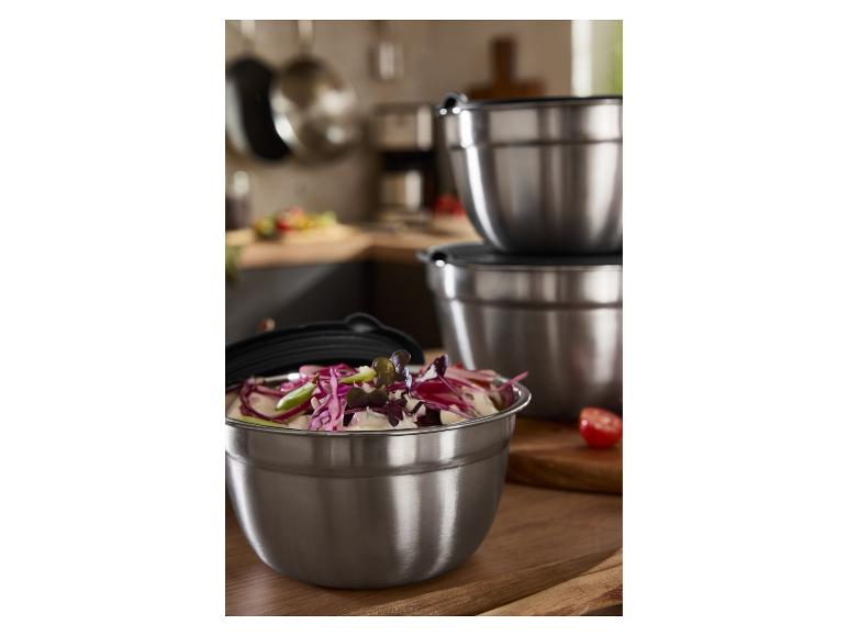 Nerezové miešacie misy s viečkami, jedna plná šalátu, v kuchyni.