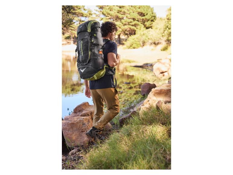 Turističný batoh a turistické topánky pri jazere.