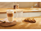 Latte v dvojstennej sklenici a biscotti na drevenom stole.