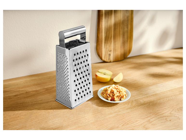 Nerezové strúhadlo so strúhanými jablkami na drevenej doske.