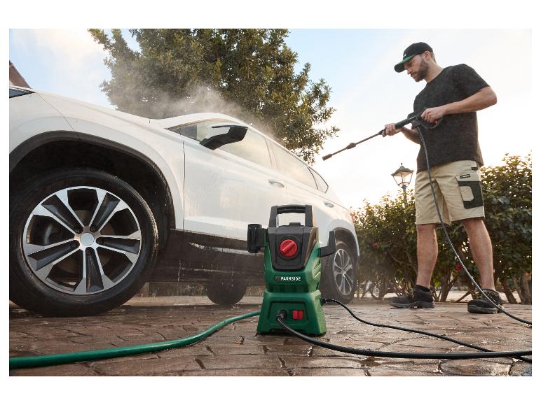 Muž umýva biele auto vysokotlakovým čističom Parkside.