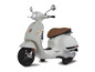 Biely skúter Vespa s hnedým sedadlom.