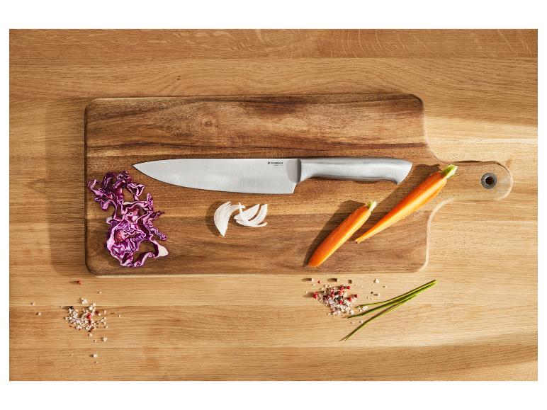 Kuchársky nôž na drevenej doske na krájanie, s červenou kapustou, cibuľou, mrkvou a koreninami.