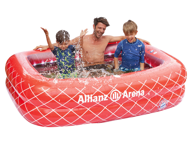Dospelý a dve deti sa hrajú v nafukovacím bazéne Allianz Arena.