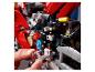 Osoba skladá červenú motorku LEGO Technic s viditeľnými prevodmi.