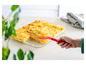 Tanier s pečeným zemiakovým gratinom, ktorý sa podáva červenou špachtľou.