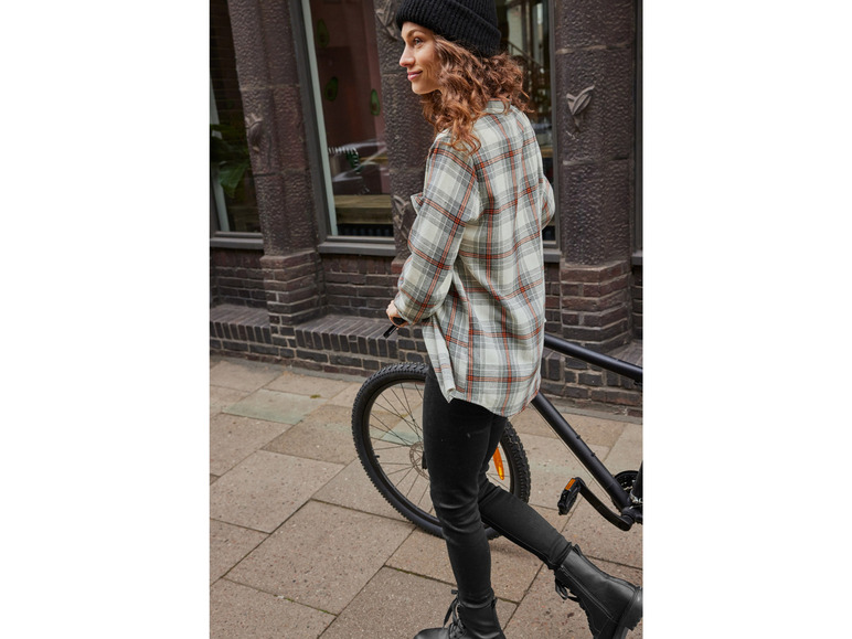 Žena v kockovanej košeli jazdí na bicykli.