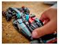 Ruka umiestňuje pretekárske auto Lego Mercedes-AMG F1 na korkový povrch.