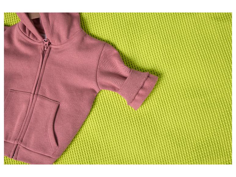 Ružová mikina s kapucňou na textúrovanej limetkovo zelenej deke.