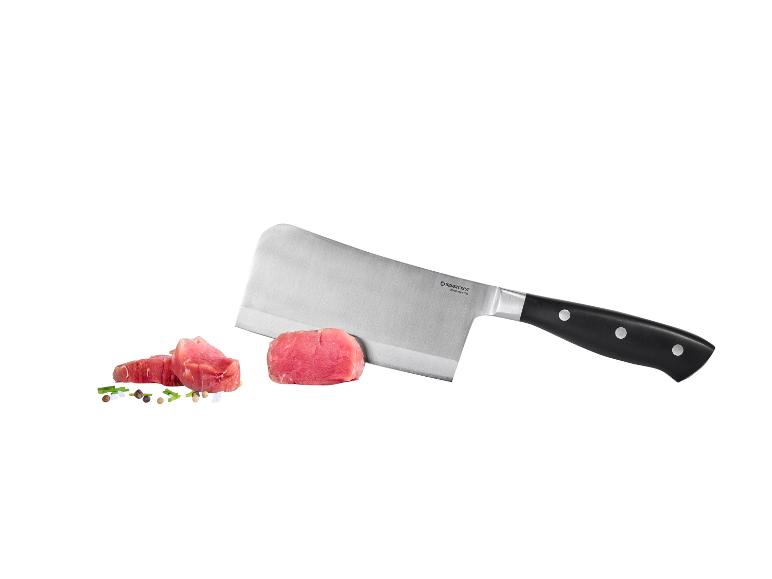 Mäsiarsky nôž s kúskami surového mäsa a koreninami.