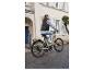 Žena jazdí na béžovom elektrickom bicykli po meste.
