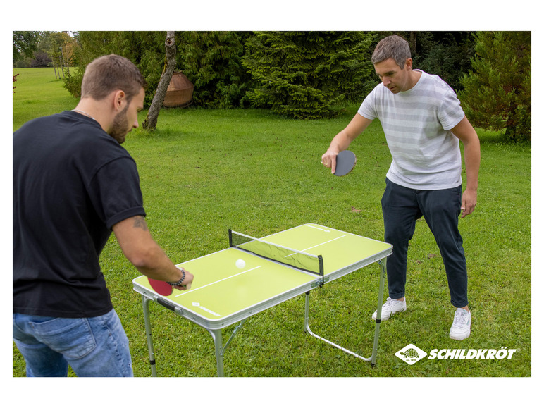 Dvaja muži hrajú stolný tenis na stole Schildkröt v záhrade.