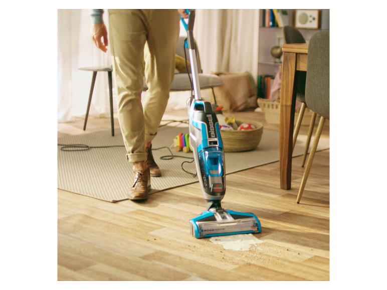 Muž používa vysávač Bissell Crosswave na drevenej podlahe.