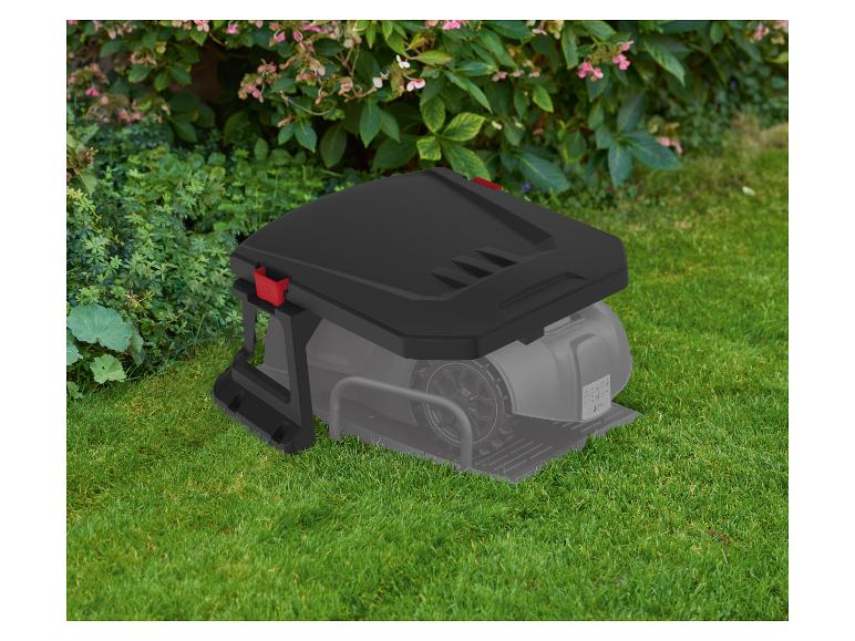 Robotická kosačka s nabíjacou stanicou na zelenej tráve pred kríkmi.