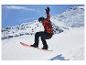 Snowboardista v červeno-čiernej bunde, čiernych nohaviciach, prilbe a okuliaroch, vo vzduchu.