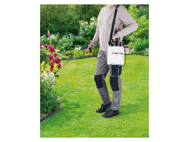 Osoba používajúca tlakový postrekovač PARKSIDE v kvitnúcej záhrade.