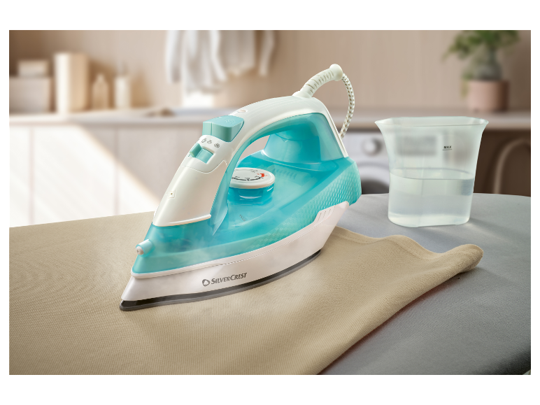 Parná žehlička Silvercrest žehlí béžovú látku na žehliacej doske.