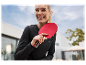 Žena s úsmevom drží červenú raketu na stolný tenis.