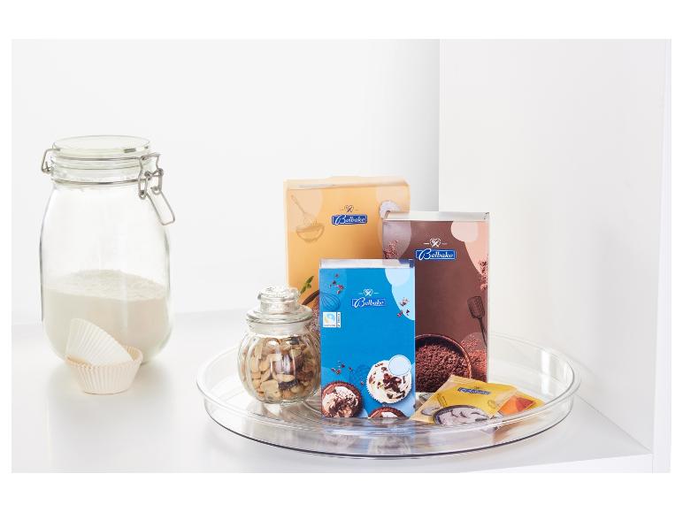 Pečivové potreby vrátane zmesí na pečenie Belbake, orechov a papierových foriem na muffiny na otočnom tanieri.