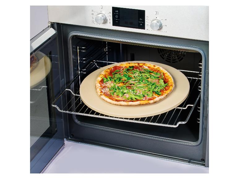 Pizza s rukolou a prosciuttom na kameni na pizzu v otvorenej rúre.