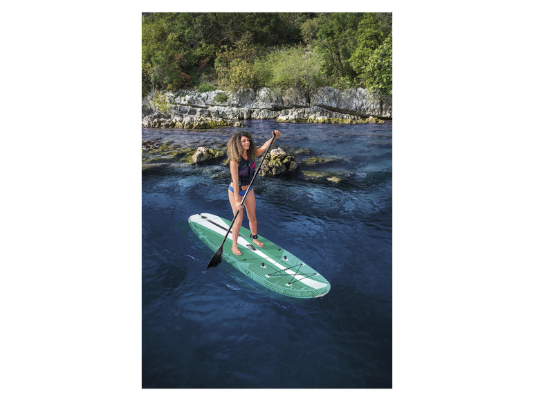 Žena pádluje na zelenej paddleboarde vo vode.