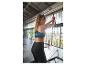Žena v čiernom športovom oblečení cvičiaca na fitness stroji.
