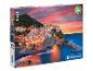 Krabica s 1000-dielovou puzzle značky Clementoni zobrazujúcou talianske mesto pri mori počas západu slnka.