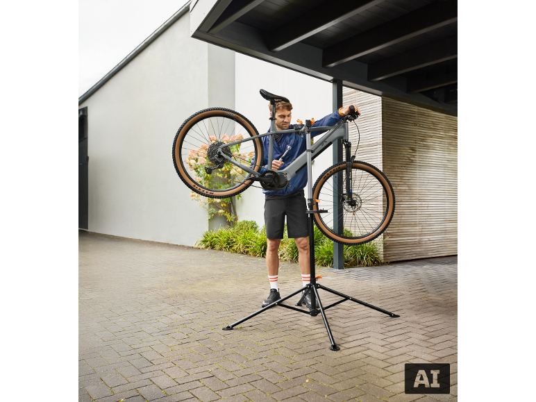Muž opravuje bicykel na stojane na opravu bicyklov vonku.