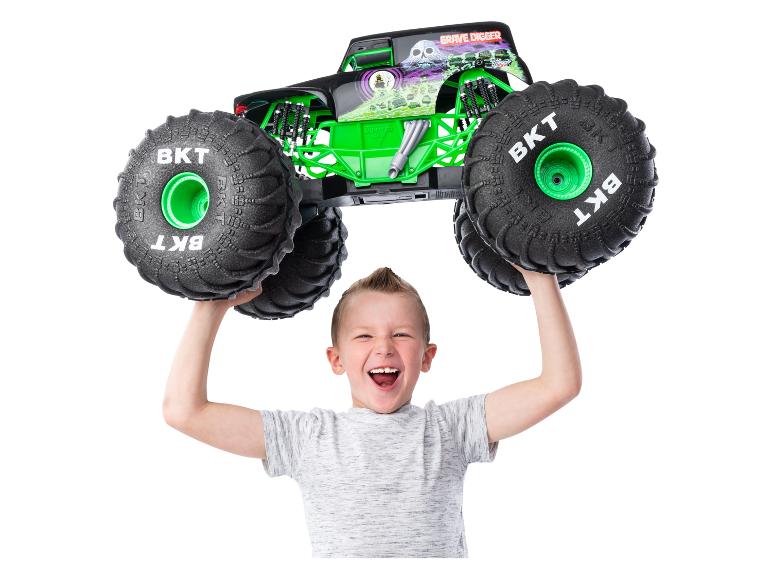 Chlapec drží hračku monster truck Grave Digger Monster Jam nad hlavou.