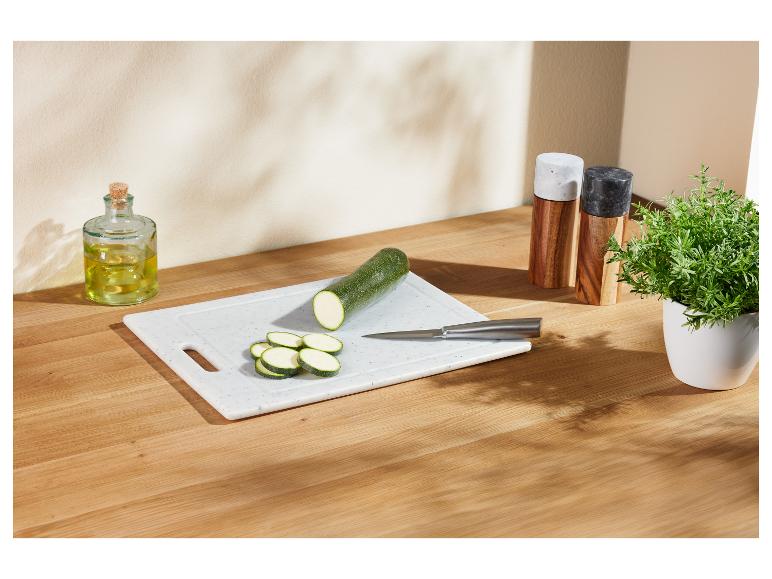 Nakrájané cukety na doske na krájanie, s olivovým olejom a bylinkami.