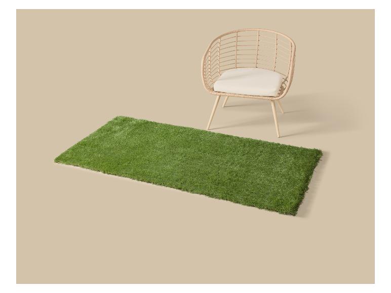 Zelený koberec z umelej trávy s prútenou stoličkou s vankúšom.