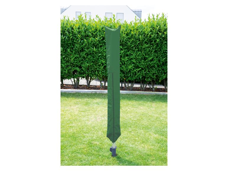 Zelený obal na otočný sušiak na bielizeň v záhrade so živým plotom a domom v pozadí.