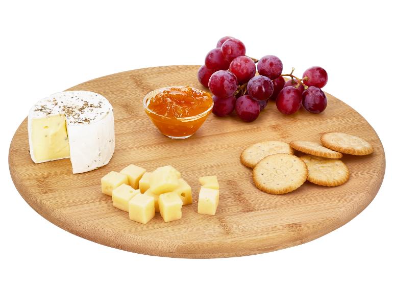 Syrová doska s brie, kockami syra, krekrami, džemom a červeným hroznom.