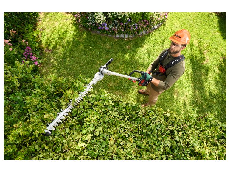 Muž používa elektrické nožnice na živý plot Parkside na strihanie živého plota.