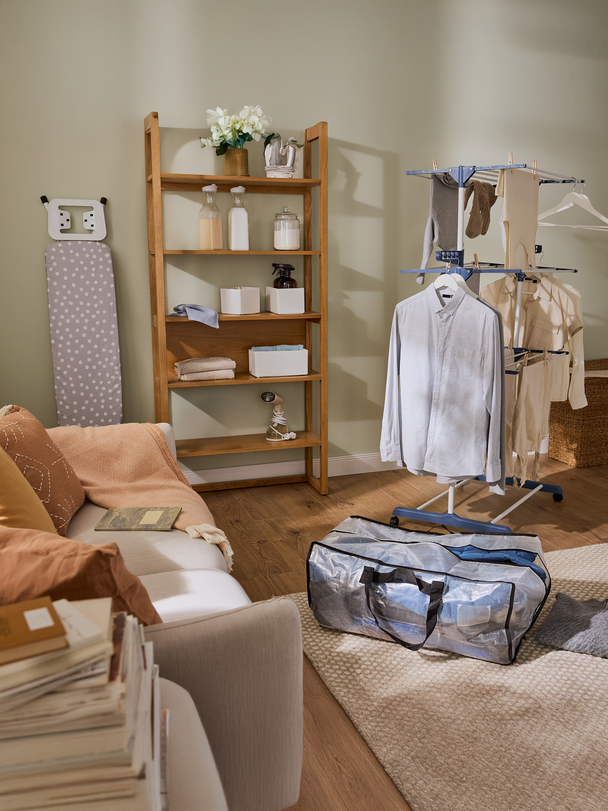 Práčovňa s drevenou policou, žehliacou doskou a sušiakom na bielizeň s oblečením.