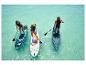 Tri osoby robia paddleboarding na tyrkysovej vode. Viditeľné sú nafukovacie SUP dosky.