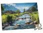 Čiastočne dokončené puzzle zobrazujúce horskú dedinu s riekou a domami.