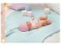 Bábika Baby Born s ružovou čiapku a cumlíkom leží na modrej deke.