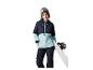 Žena s lyžiarskymi okuliarmi a snowboardom, v zimnej bunde a nohaviciach.