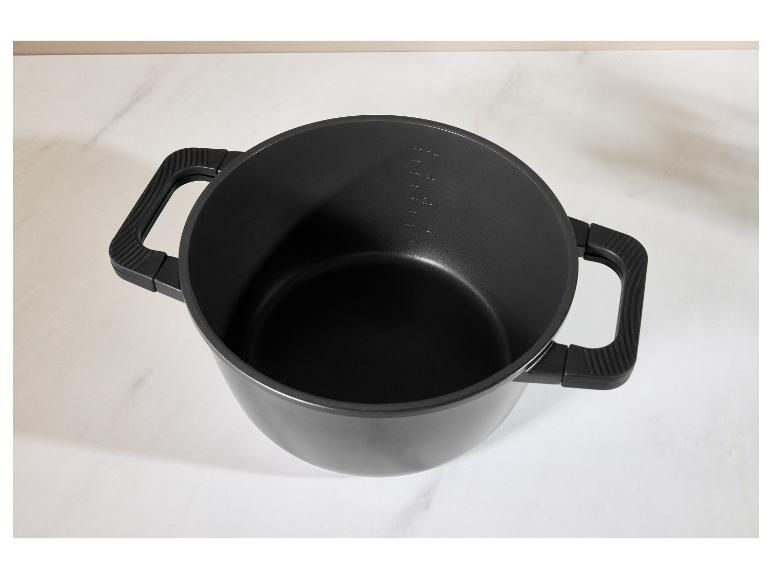 Čierny hrniec s rúčkami a meracími značkami na bielom povrchu
