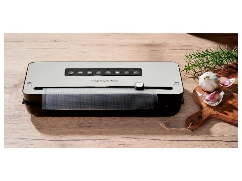 Vákuová zváračka SilverCrest na drevenom stole s cesnakom a rozmarínom.