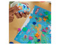 Dieťa sa hrá s Play-Doh, modrou batožinou a mapou sveta.