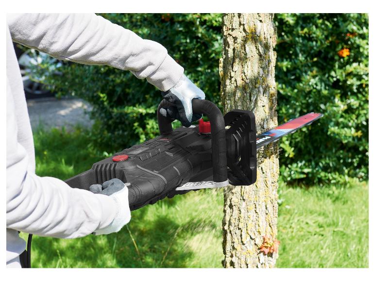 Osoba používa elektrickú reťazovú pílu na prerezávanie stromu.