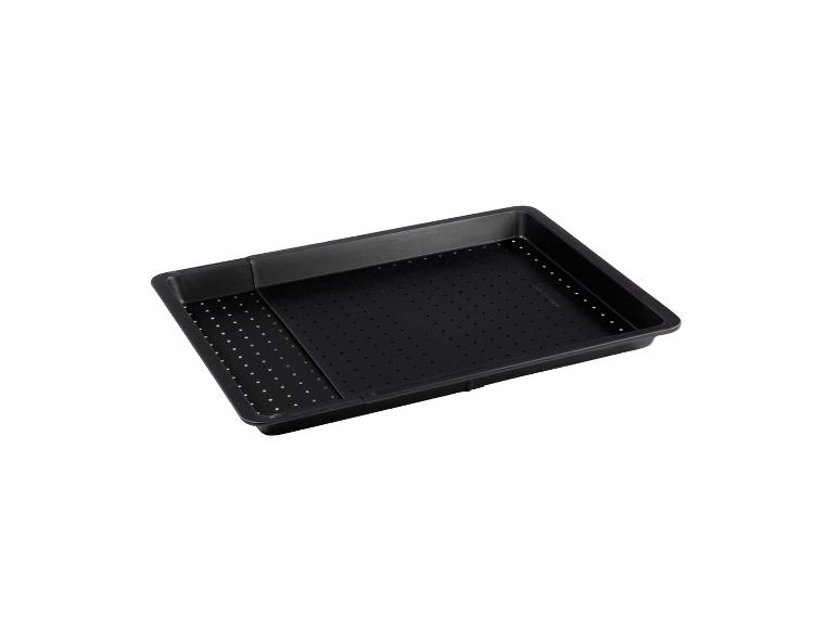 Čierna plech na pečenie s perforovaným dnom.