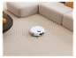 Robot vysávač na koberci, pri sedačke.