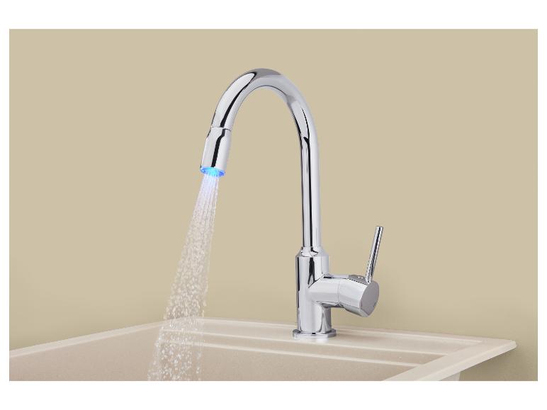 Chrómová kuchynská batéria s výsuvnou sprchou a LED svetlom, nad béžovým drezom.