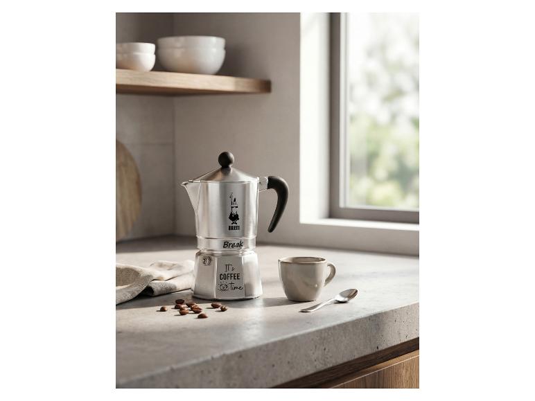 Strieborný kávovar s nápisom „It's coffee time“ a šálka na kuchynskej linke.