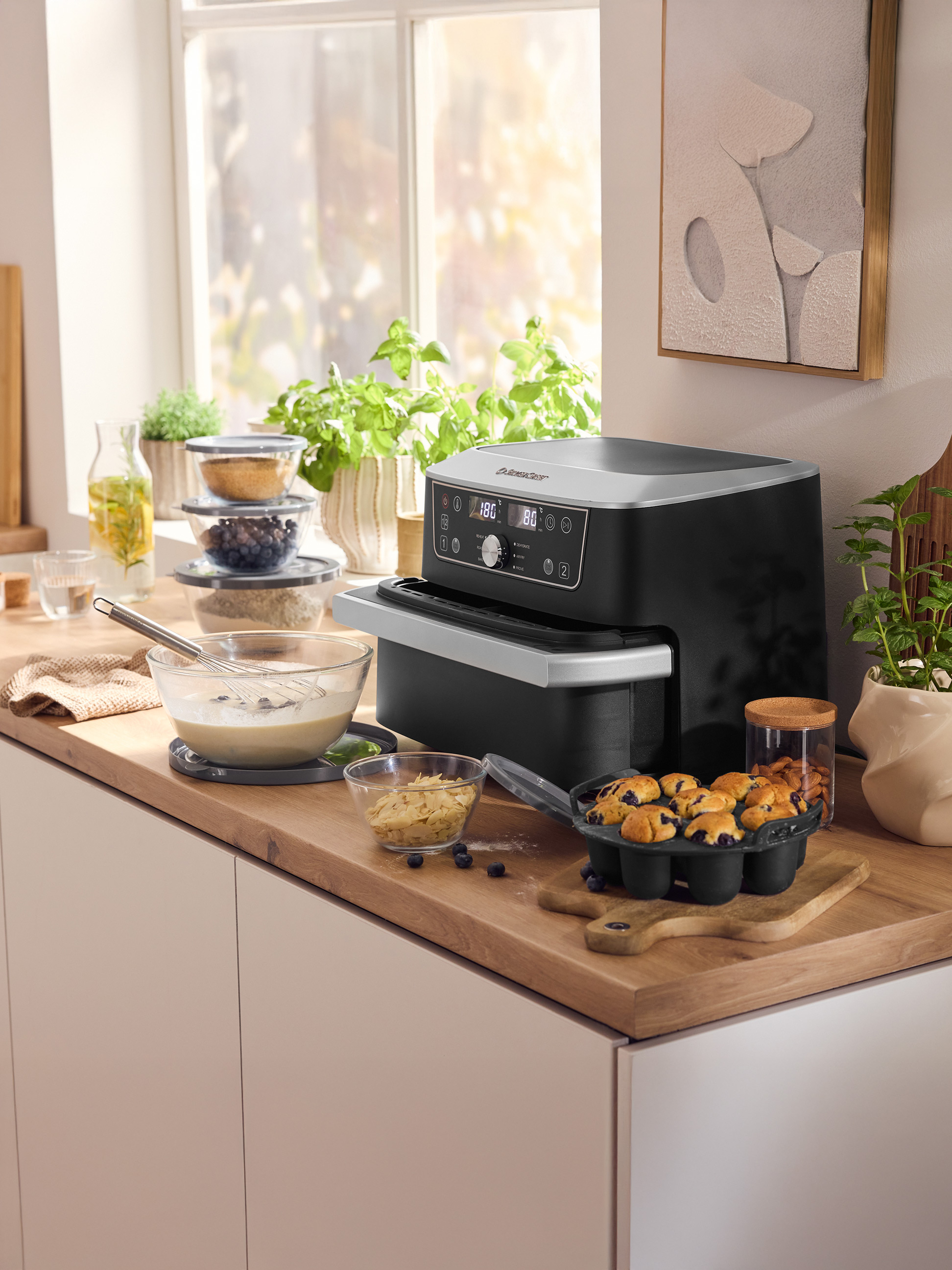 Kuchynská linka so vzduchovou fritézou Silvercrest, formou na muffiny s čučoriedkovými muffinmi a prísadami na pečenie.