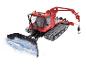 Červený snežný ratrak PistenBully 600 s radlicou a zdvíhacím ramenom.