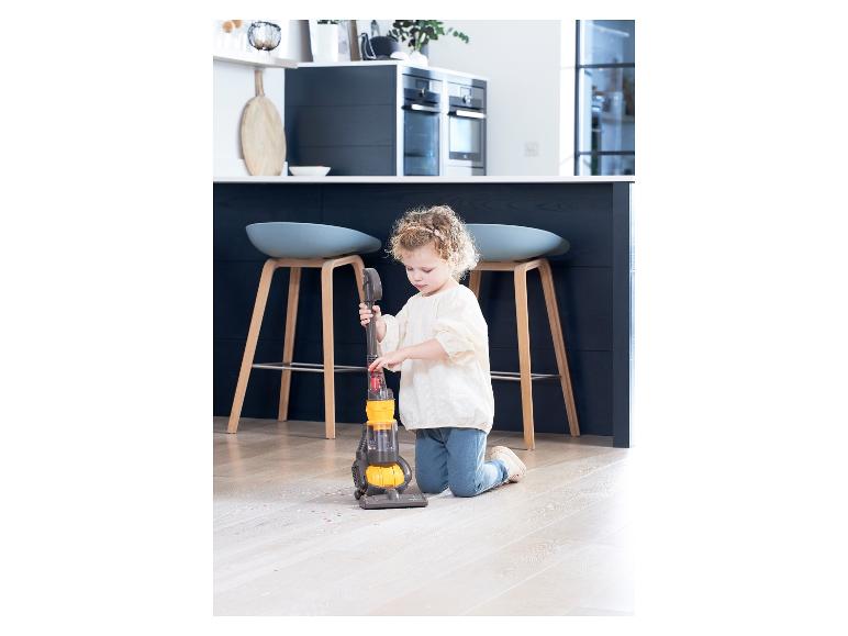 Dieťa vysáva podlahu hračkárskym vysávačom Dyson.